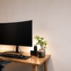 湾曲モニターとキーボードを余裕のある木製デスクに配置した作業環境