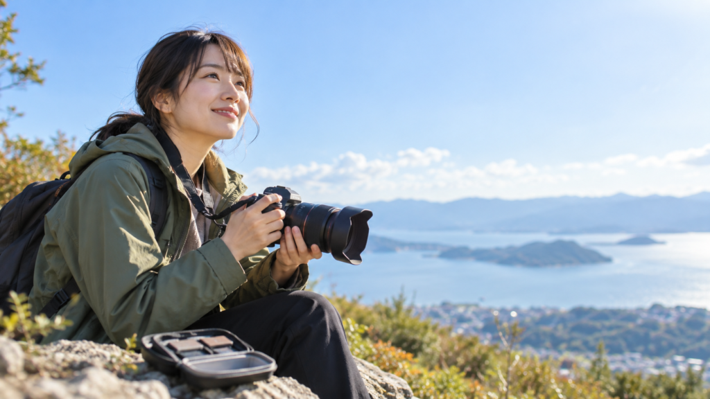 湖と山を望む屋外でカメラを構え、足元に開いたメモリーカードケースを置く女性