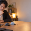 デスク上の黒と淡いグレーのエルゴノミクスマウスを前に、ノートPCを見ながら購入モデルを検討する男性