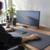 広いマウスパッド上で、手のひらを載せたまま大型マウスを滑らせて操作するデスクワーク中の男性