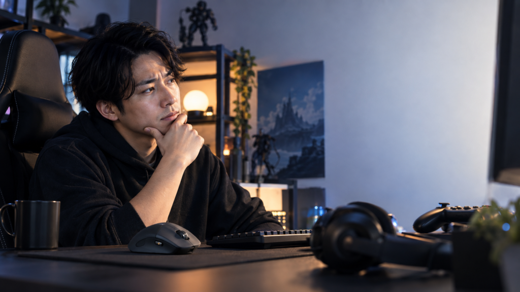 多ボタンのエルゴノミクスマウスとキーボード、ヘッドセットを置いたゲーム環境でモニターを見る男性